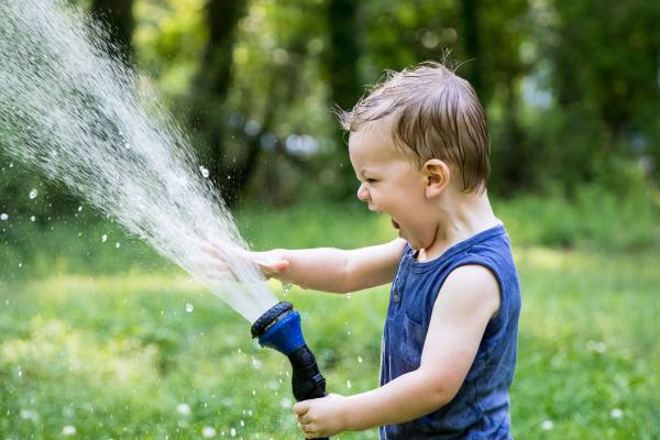 delighted toddler playing with water hose